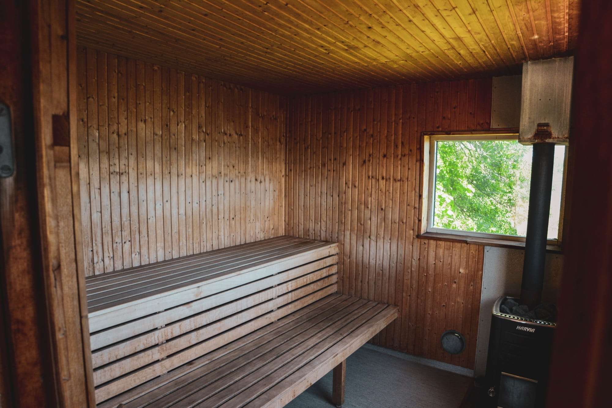 Bastun inifrån, med träpanel, lavar i två steg, litet fönster och vedeldad kamin.
